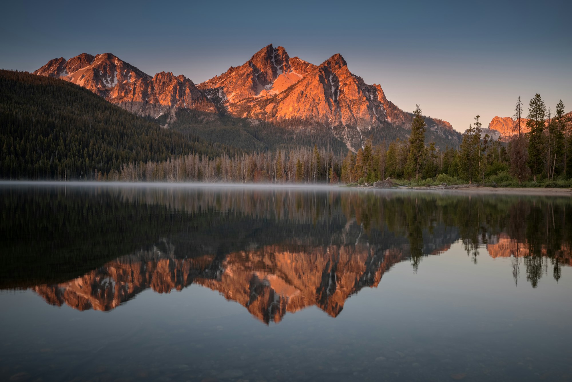 The Sawtooth Mountains of central Idaho at sunrise, reflected in a still alpine lake — a draw for veterans relocating to the Treasure Valley