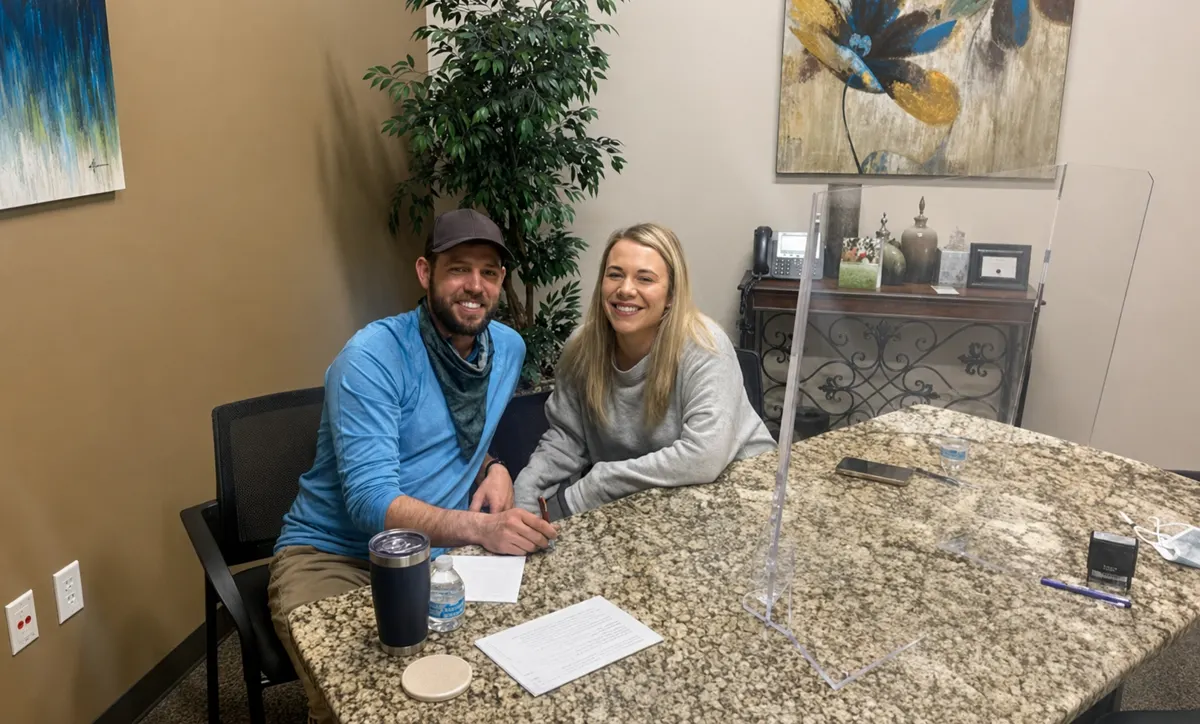 Two buyers signing closing paperwork at a conference table