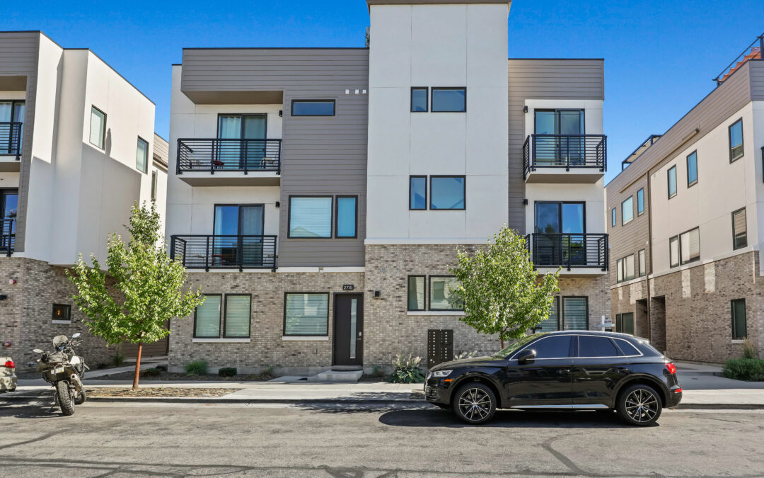 Modern multi-story townhouse with brick and panel siding, black railing balconies, and a clean streetscape.