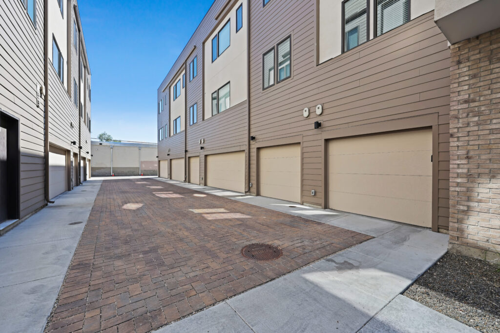 Garage Access View – Rear of Townhomes - Good News Realty Group Rear alleyway with multiple garages and modern cladding.