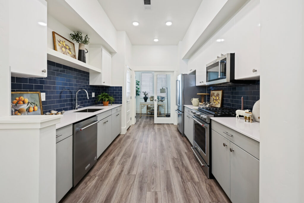 Modern Kitchen Overview – 2719 W Stewart Ave - Good News Realty Group Sleek galley kitchen with blue subway tile backsplash, white cabinetry, and stainless appliances.