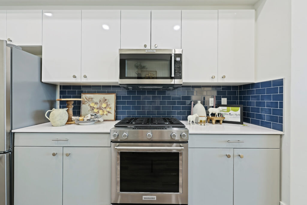 Cooking Station with Microwave and Range - Good News Realty Group Stainless steel gas range and microwave with white cabinetry and dark blue backsplash.