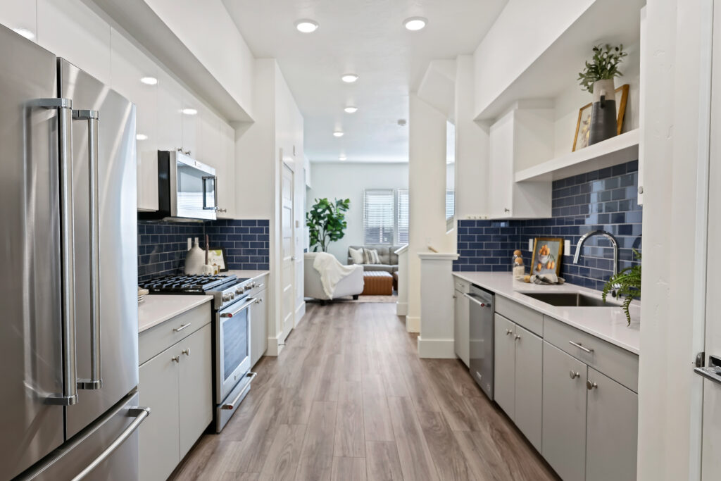 Kitchen to Living Room Flow - Good News Realty Group View from kitchen through open space to a cozy living room with neutral tones.