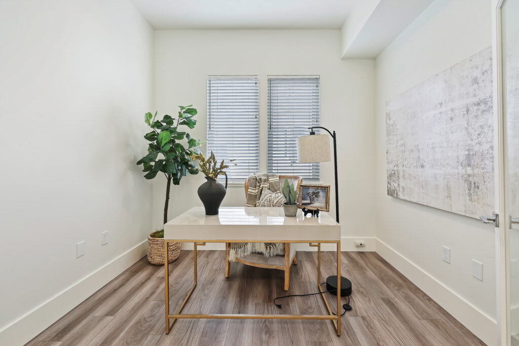 Private Office or Reading Nook - Good News Realty Group Minimalist home office with white desk, indoor plant, and two front-facing windows.
