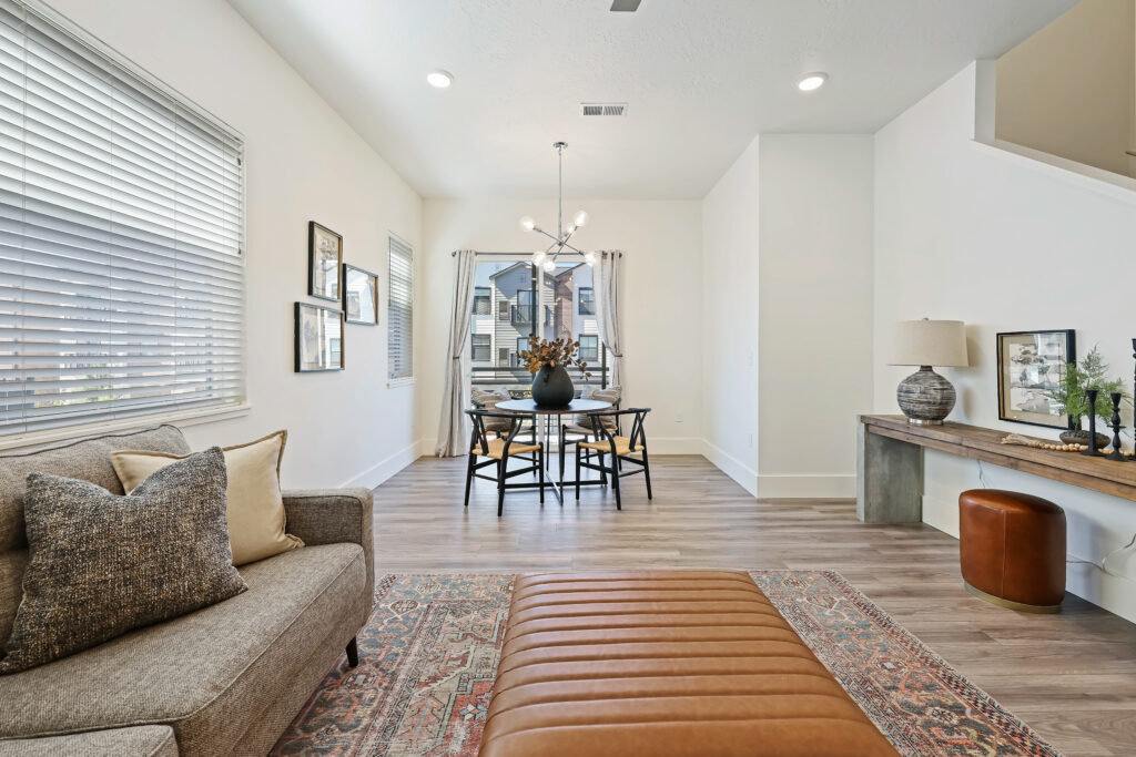 Dining Area with Balcony Views - Good News Realty Group Contemporary dining space with black chairs and glass table near a window-lined wall.