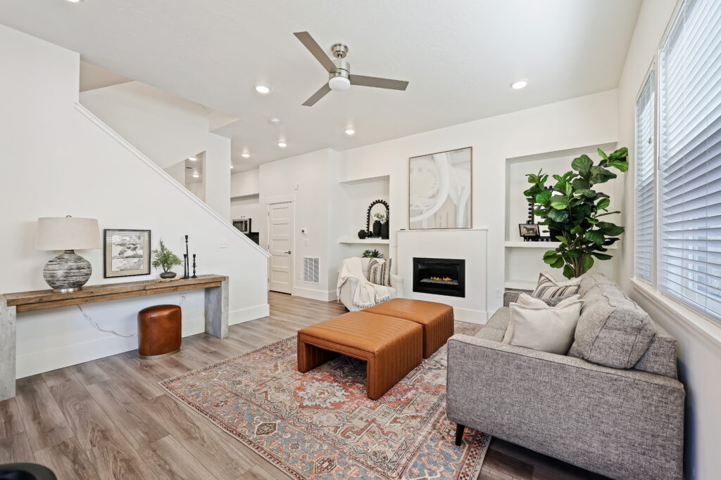 Living Room with Fireplace and Staircase View - Good News Realty Group Living area with fireplace, built-ins, accent rug, and staircase in background.
