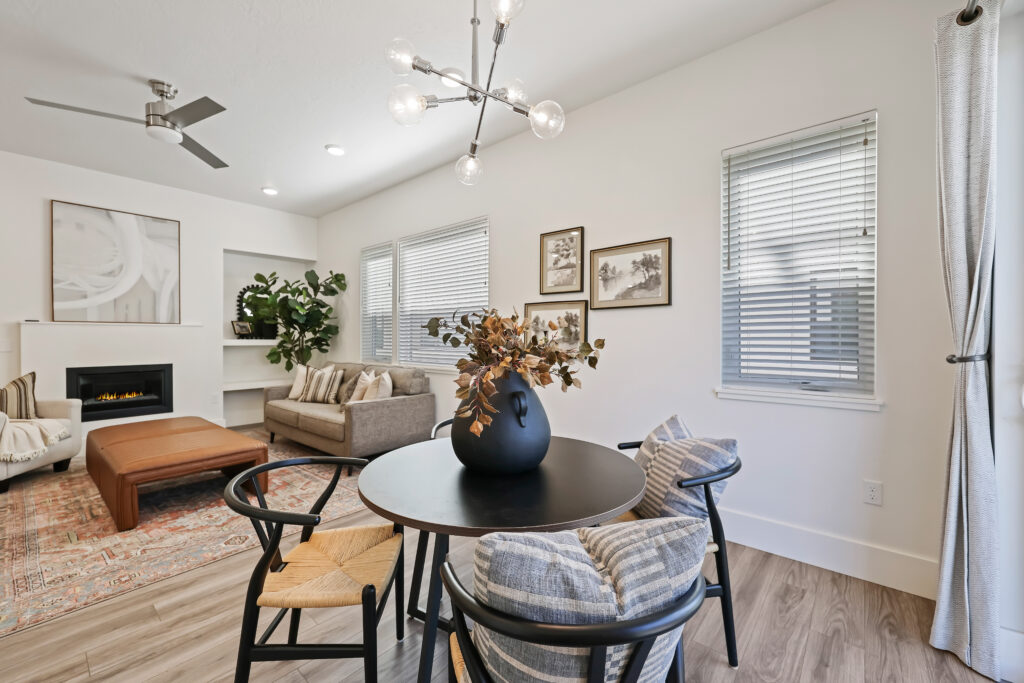 Dining Area Beside Fireplace - Good News Realty Group Dining space adjacent to living room with black table, modern light fixture, and wall art.
