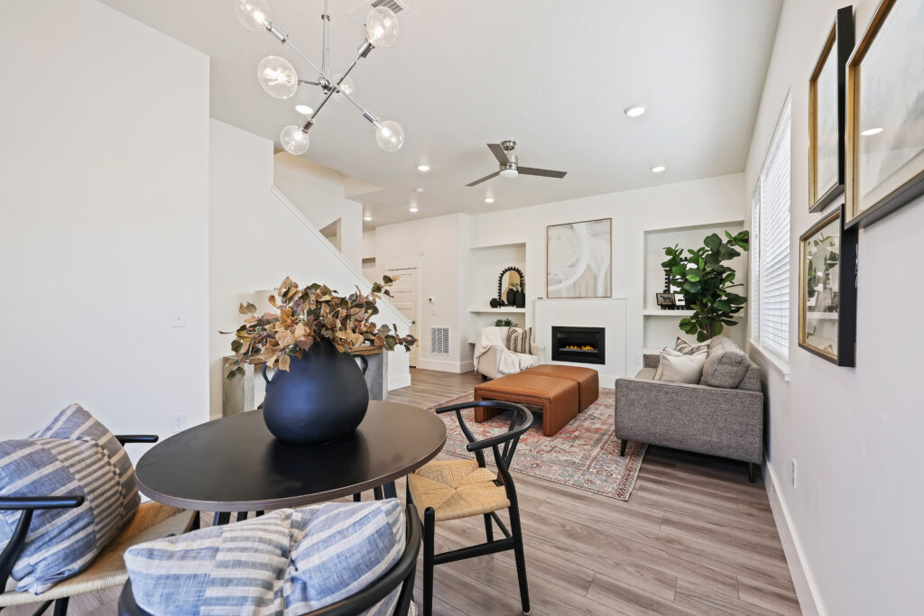 Integrated Dining and Living Room View - Good News Realty Group Round dining table in foreground with modern chandelier, fireplace and seating in background