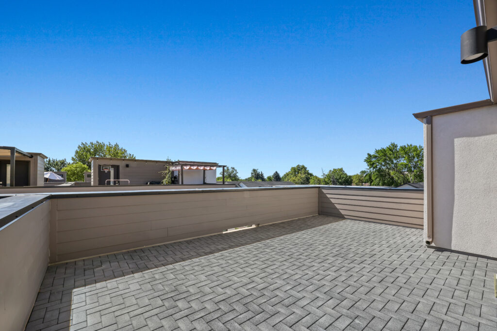 Rooftop Patio View #1 - Good News Realty Group Open rooftop deck with pavers and partial view of nearby rooftops